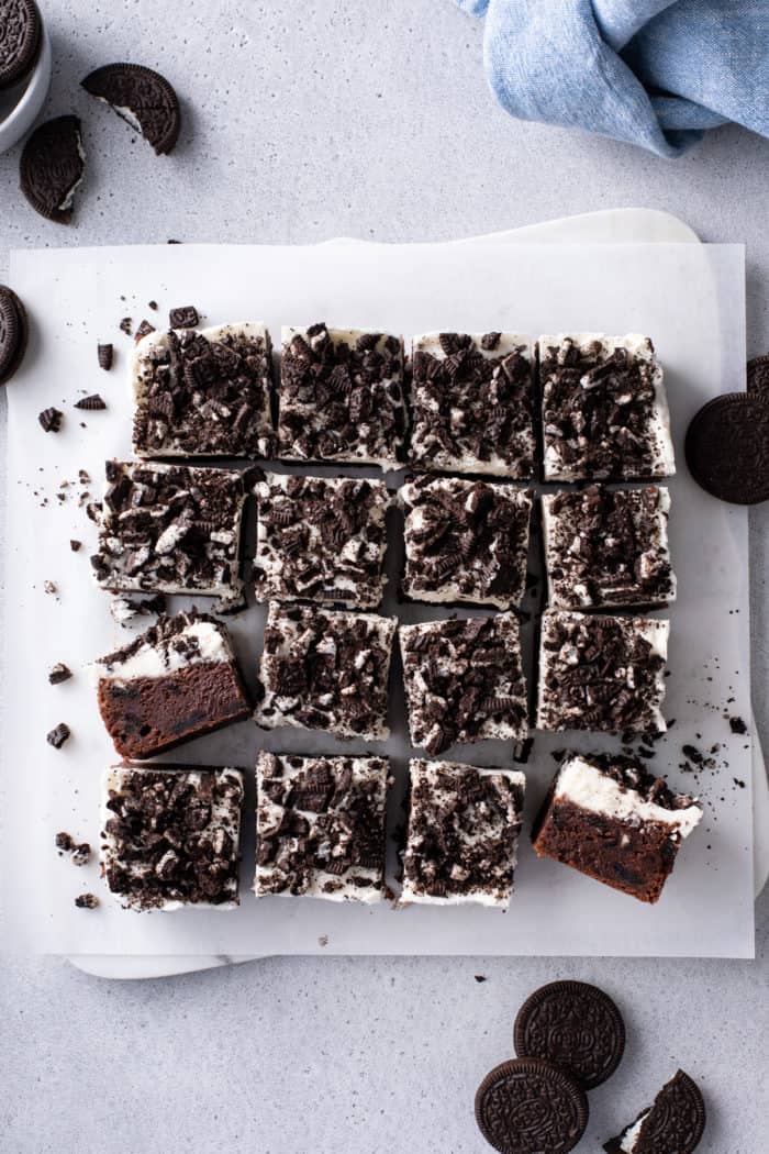 Overhead view of a pan of sliced oreo brownies on a piece of parchment paper.