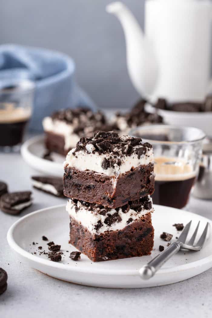 White plate holding a fork and two stacked oreo brownies.