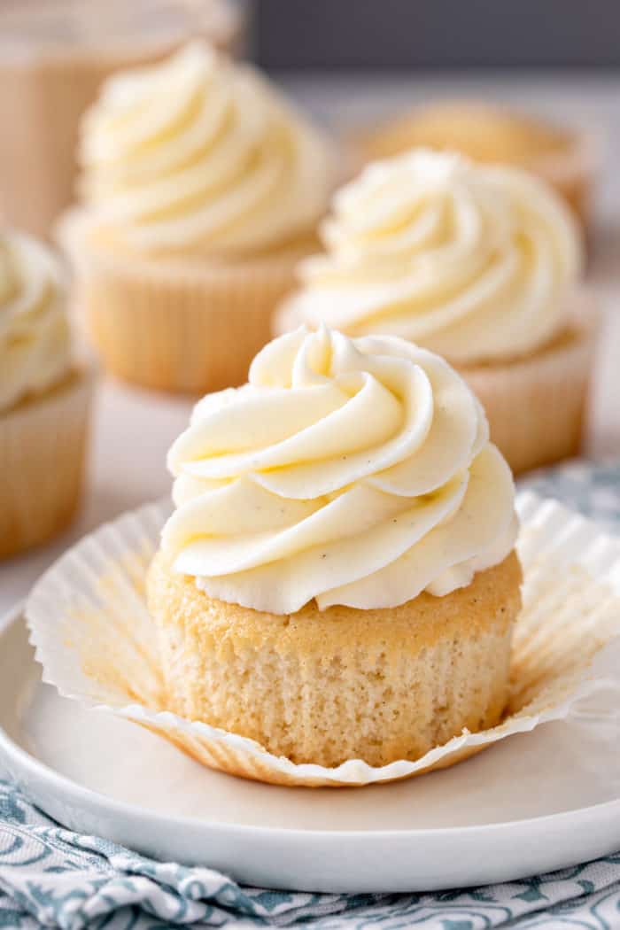 Vanilla cupcake unwrapped on a white plate.