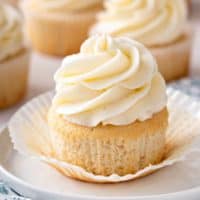 Unwrapped vanilla cupcake on a plate.
