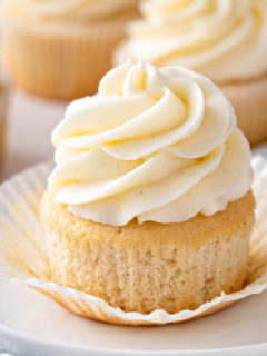 Unwrapped vanilla cupcake on a plate.