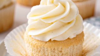 Unwrapped vanilla cupcake on a plate.