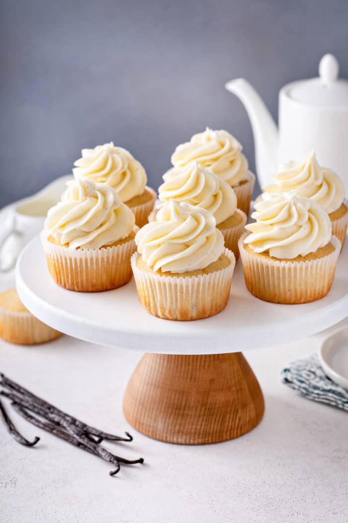 Vanilla cupcakes set on a white cake stand.