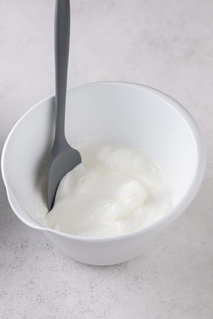 Beaten egg whites in a white mixing bowl.