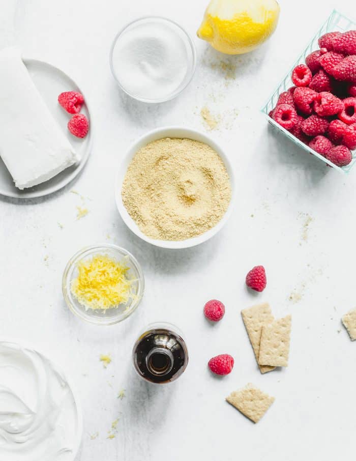 Ingredients for no bake raspberry lemon cheesecake scattered on a marble countertop