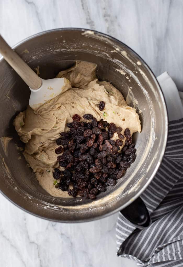 Spatula about to fold raisins into the dough for zucchini cookies