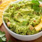 Tortilla chip in a white bowl filled with guacamole