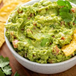 Tortilla chip in a white bowl filled with guacamole