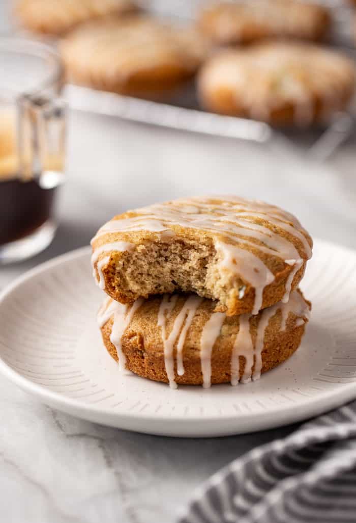 Two zucchini cookies stacked on a white plate. A bite has been taken out of the top cookie