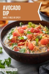 Brown bowl filled with avocado dip that has been garnished with tomatoes, cheese, and cilantro. Text overlay includes recipe name.