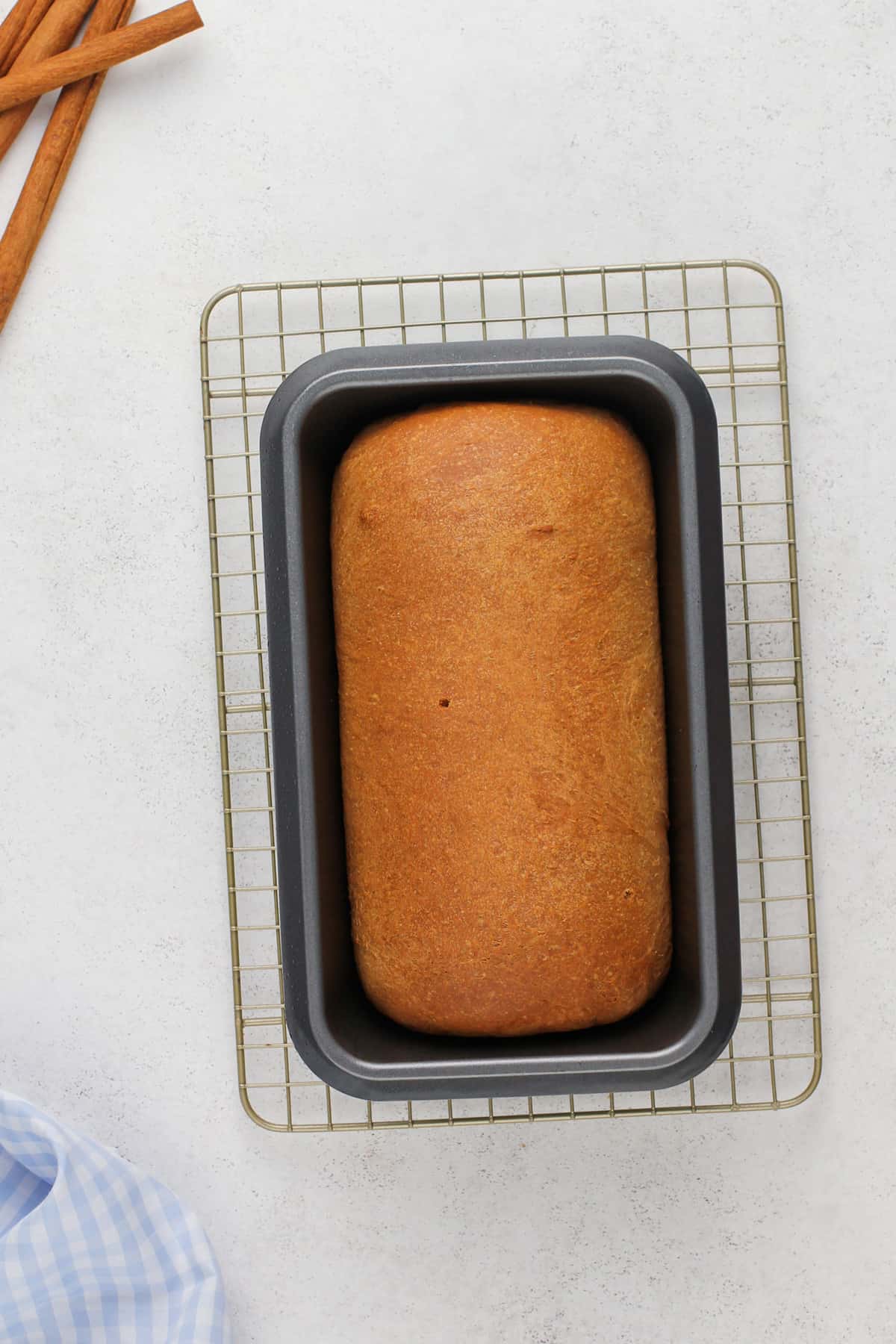 Baked loaf of cinnamon swirl bread on a wire rack.