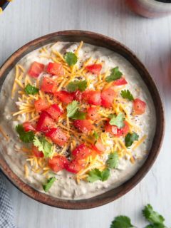 Overhead image of bowl filled with garnished avocado dip.