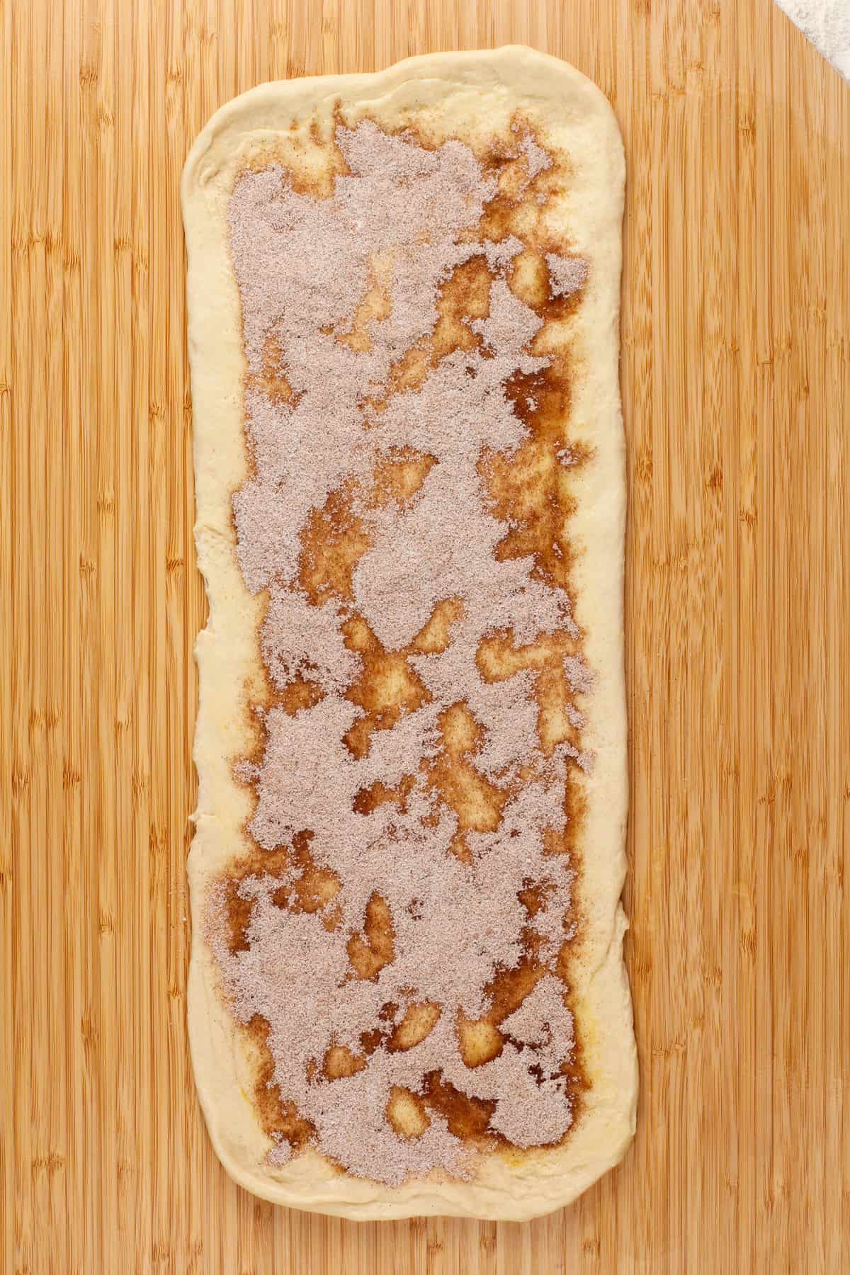 Dough rolled into a long rectangle and topped with cinnamon and sugar.