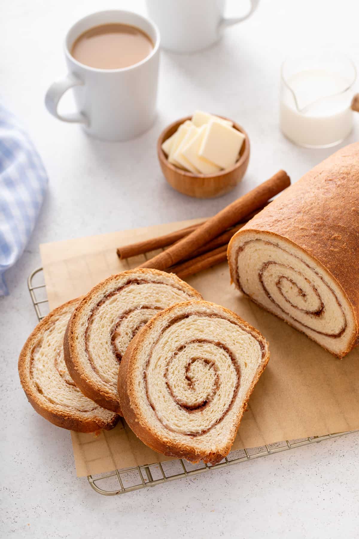 Three slices of cinnamon swirl bread on a piece of parchment paper next to the rest of the loaf.