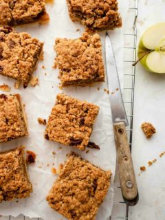 Baked apple pie bars with crumble topping, sliced and on parchment paper