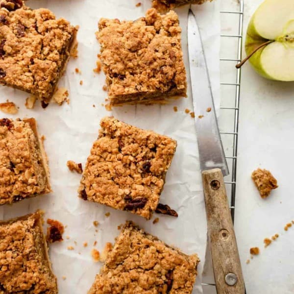 Baked apple pie bars with crumble topping, sliced and on parchment paper