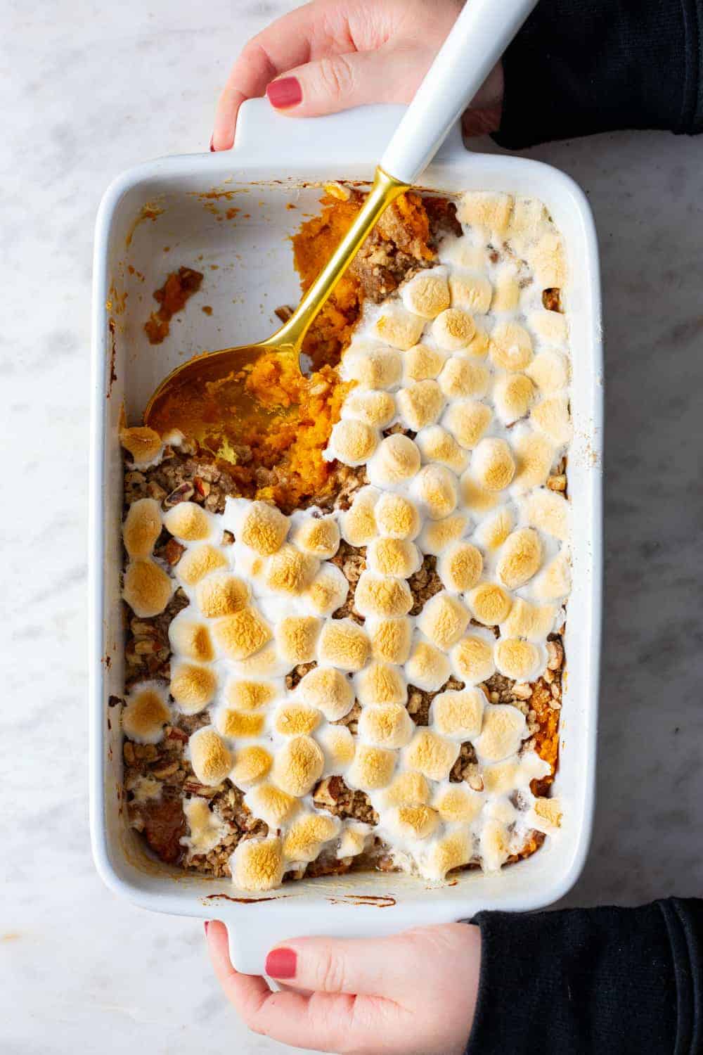 Hands placing a dish of sweet potato casserole on the countertop