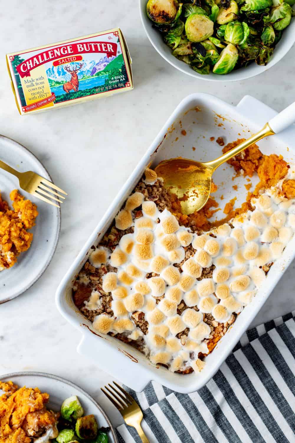 Spoon dishing out sweet potato casserole with streusel topping and sweet potatoes