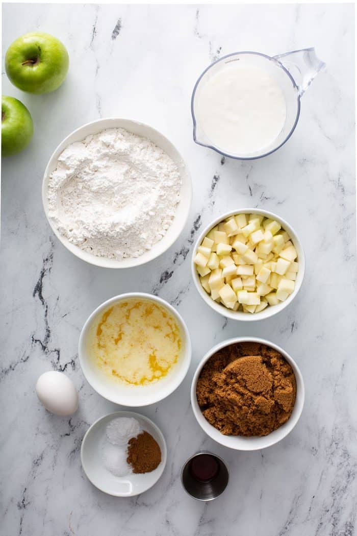 Overhead view of ingredients for apple cinnamon muffins arranged on a marble counter