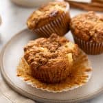 Three apple cinnamon muffins on a cream plate