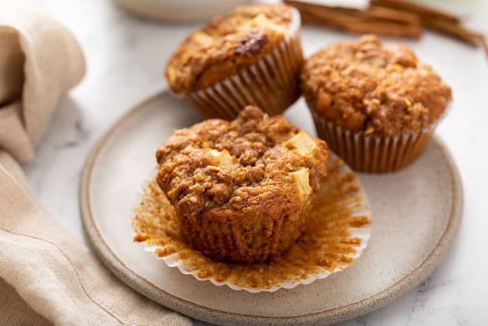 Three apple cinnamon muffins on a cream plate