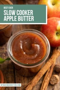 Apple butter swirled into an open glass jar that is set on a wooden tabletop. Text overlay includes recipe name.