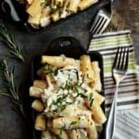 Two small baking dishes full of mac and cheese on a stone surface next to forks