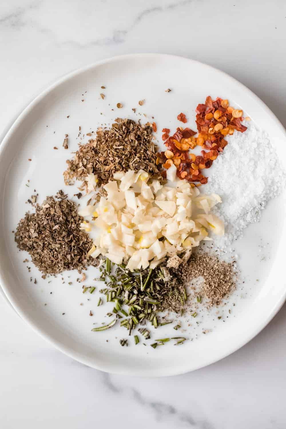 Garlic and herbs for olive oil herb dip on a white plate