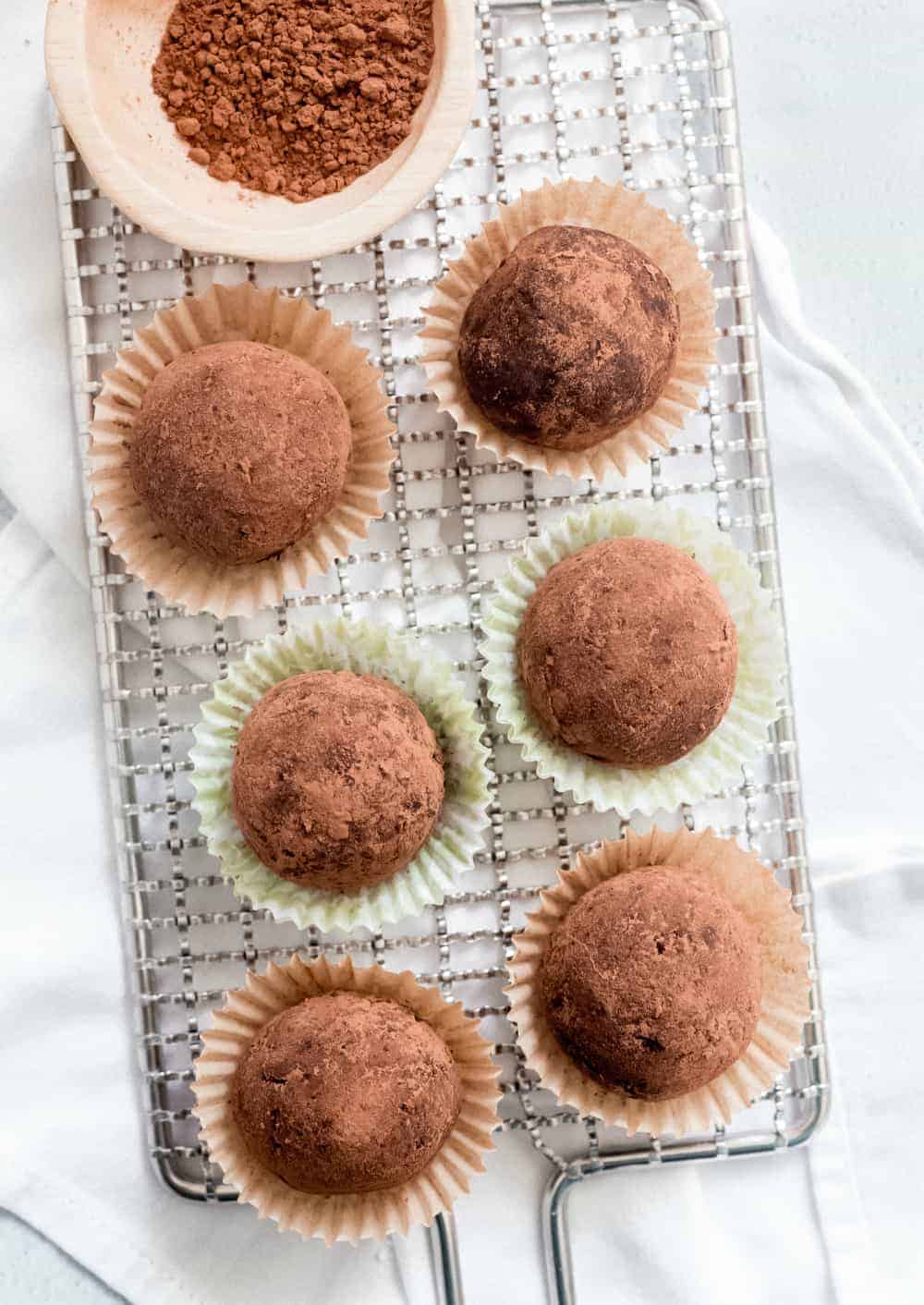 Overhead image of 6 rum balls coated in cocoa powder on a baking rack