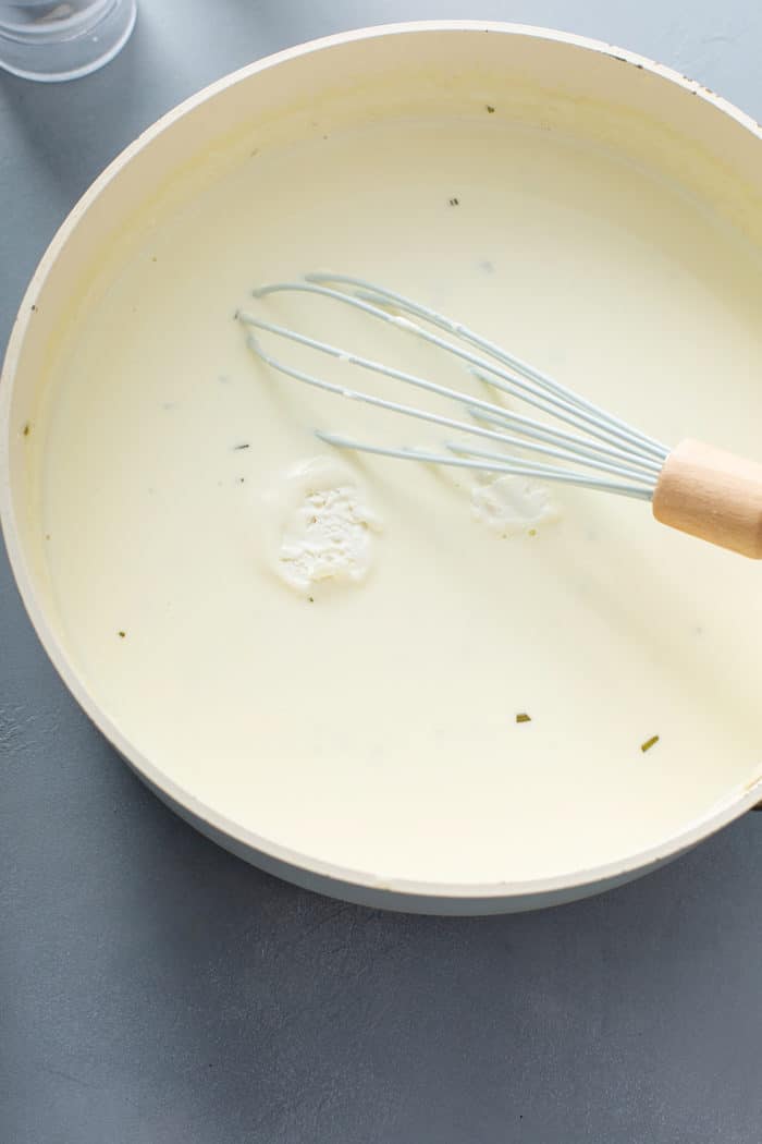 Whisk stirring rounds of goat cheese into cream sauce in a large saucepan