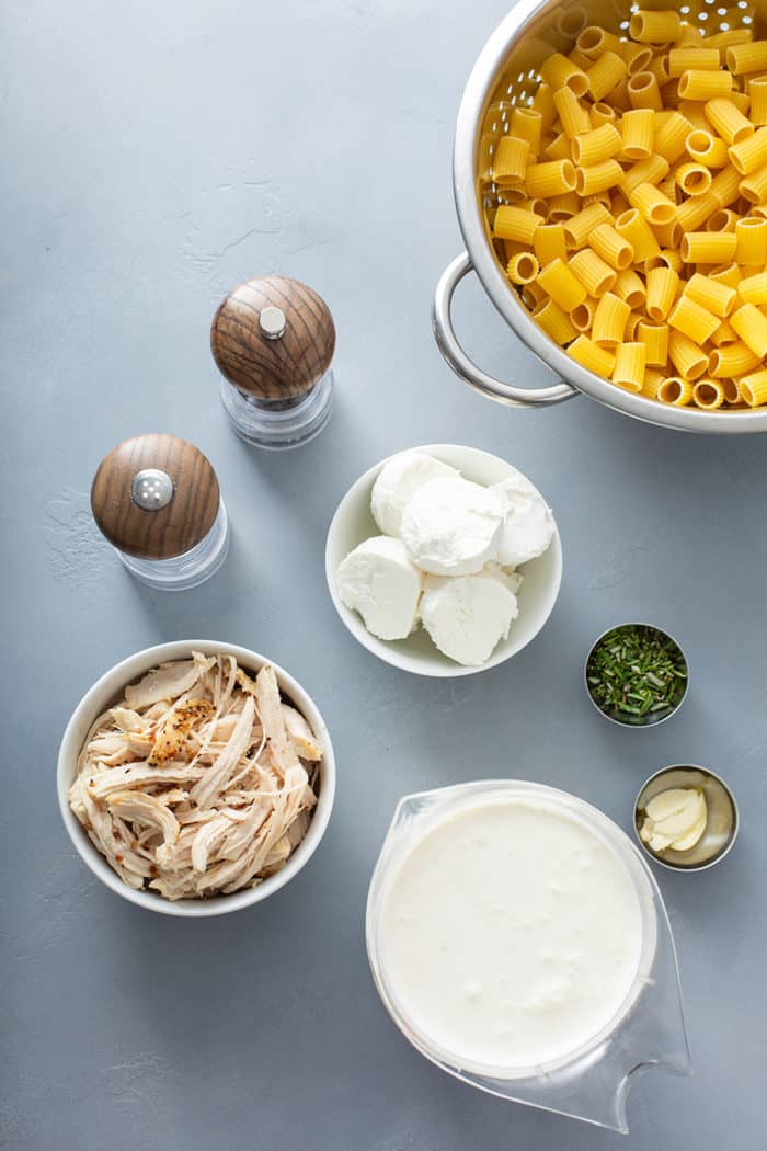 Ingredients for goat cheese pasta with chicken and rosemary on a gray countertop