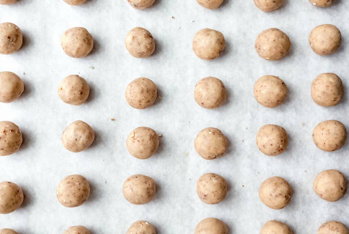 Snowball cookie dough rolled into balls and placed on parchment paper, ready to bake