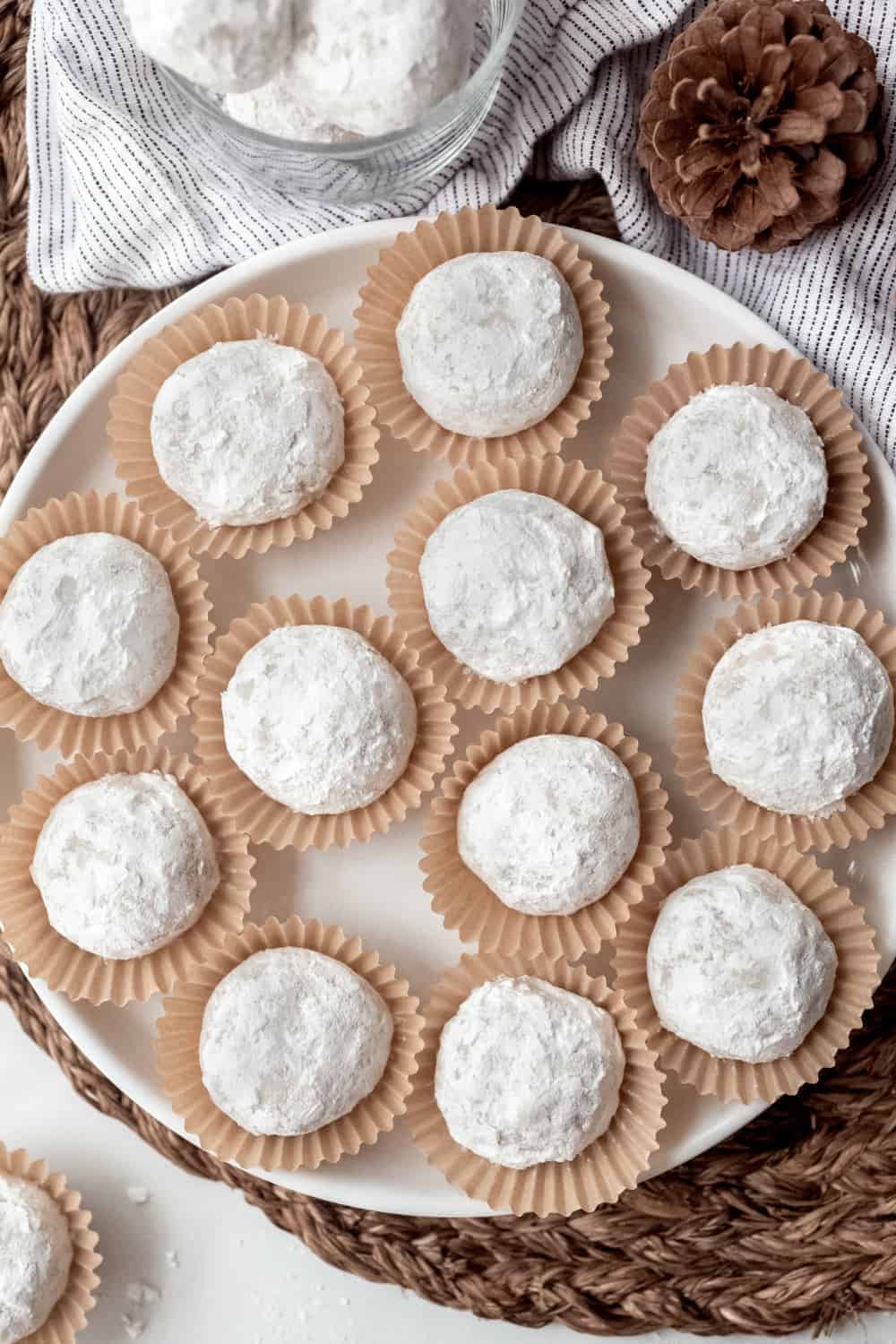 Snowball cookies in paper liners arranged on a white platter