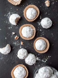 Snowball cookies arranged on a slate surface.