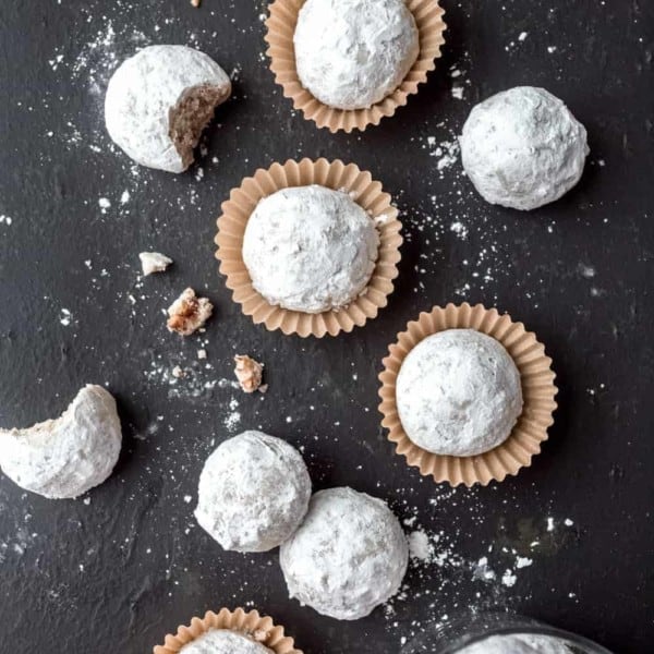 Snowball cookies arranged on a slate surface.