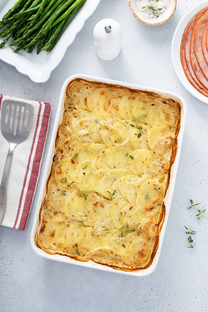 Overhead view of a casserole dish of baked scalloped potatoes on a dinner table