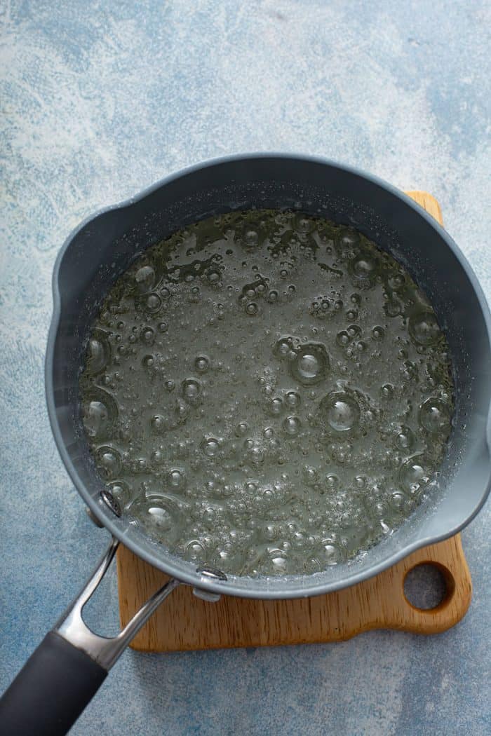 Sugar syrup boiling in a saucepan set on a countertop