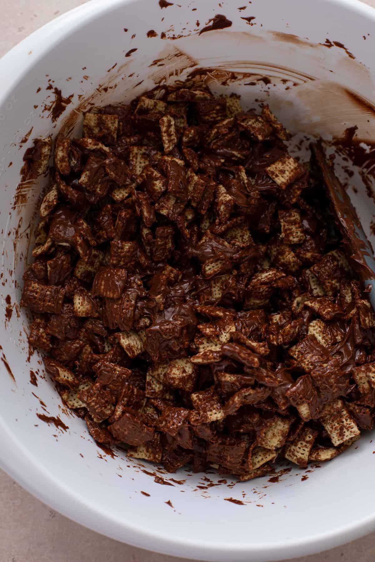 Chex cereal coated in melted chocolate and peanut butter in a bowl.