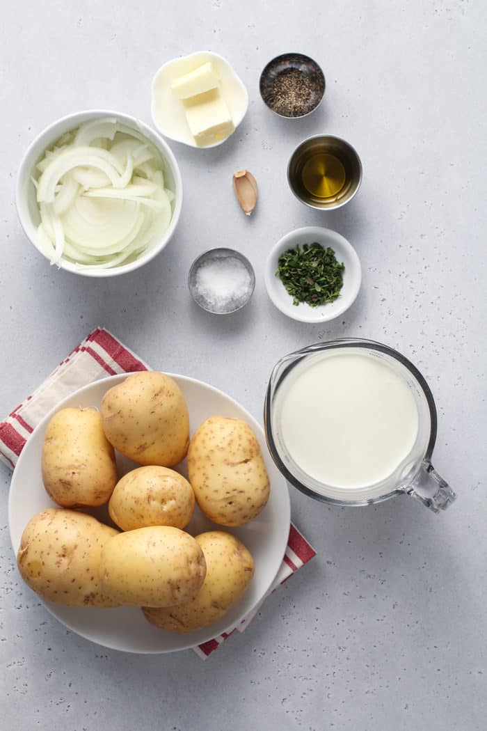 Ingredients for scalloped potatoes arranged on a gray countertop