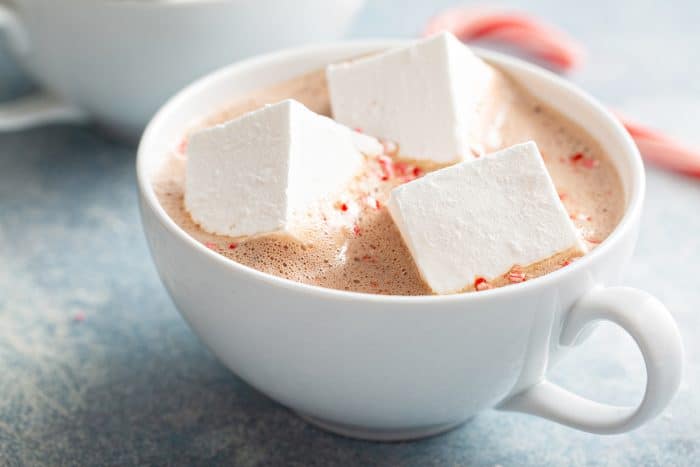 Three homemade marshmallows floating in a mug of hot chocolate