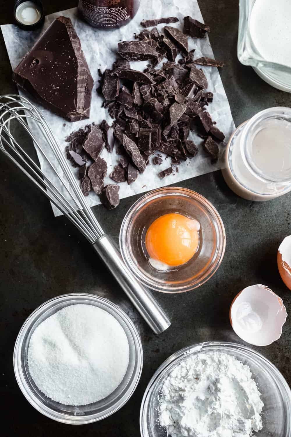 Ingredients for homemade chocolate pudding with Baileys arranged on a black countertop