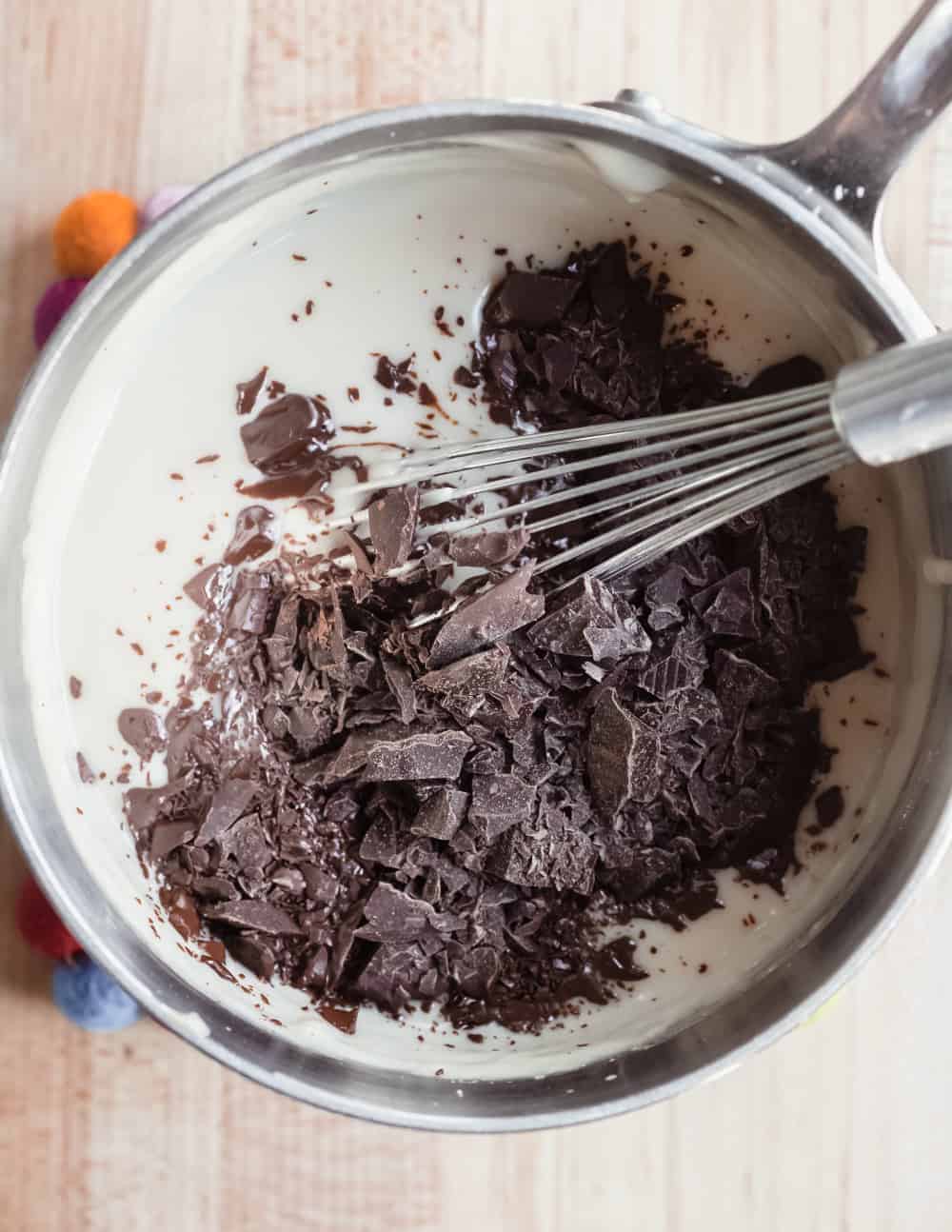 Chopped chocolate added to homemade pudding with Baileys in a saucepan