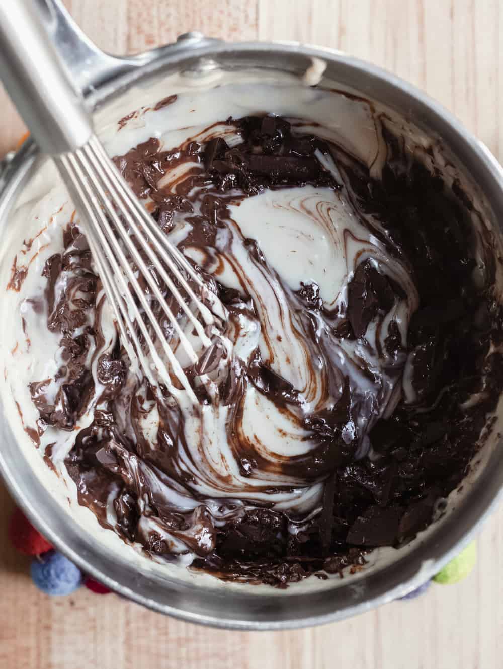 Whisk stirring melted chocolate into homemade pudding in a saucepan