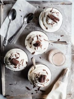 Homemade chocolate pudding in small glass dishes, topped with whipped cream and chocolate shavings
