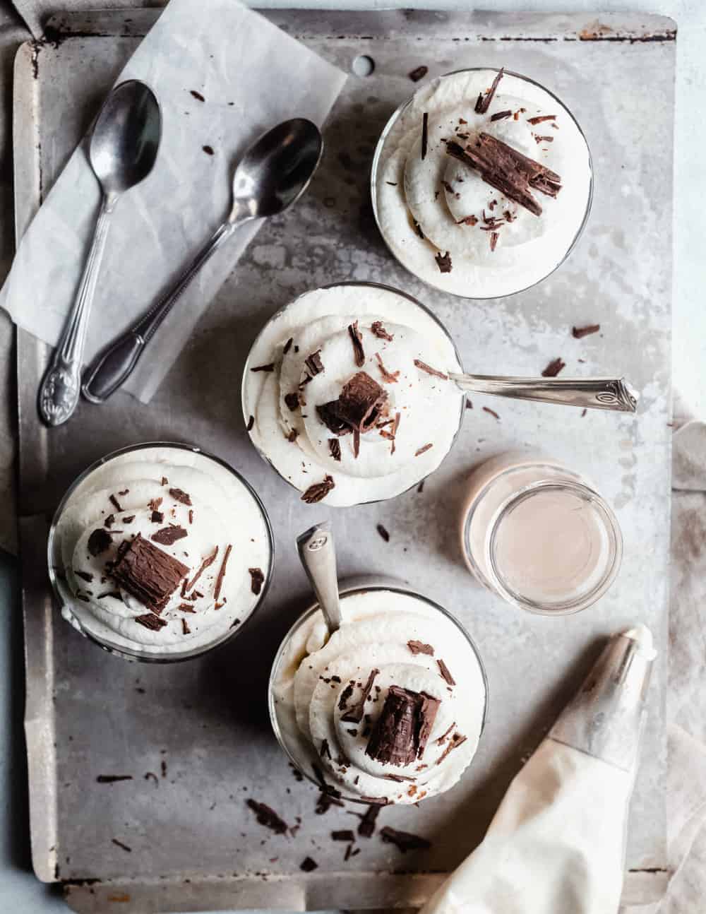 Homemade chocolate pudding in small glass dishes, topped with whipped cream and chocolate shavings