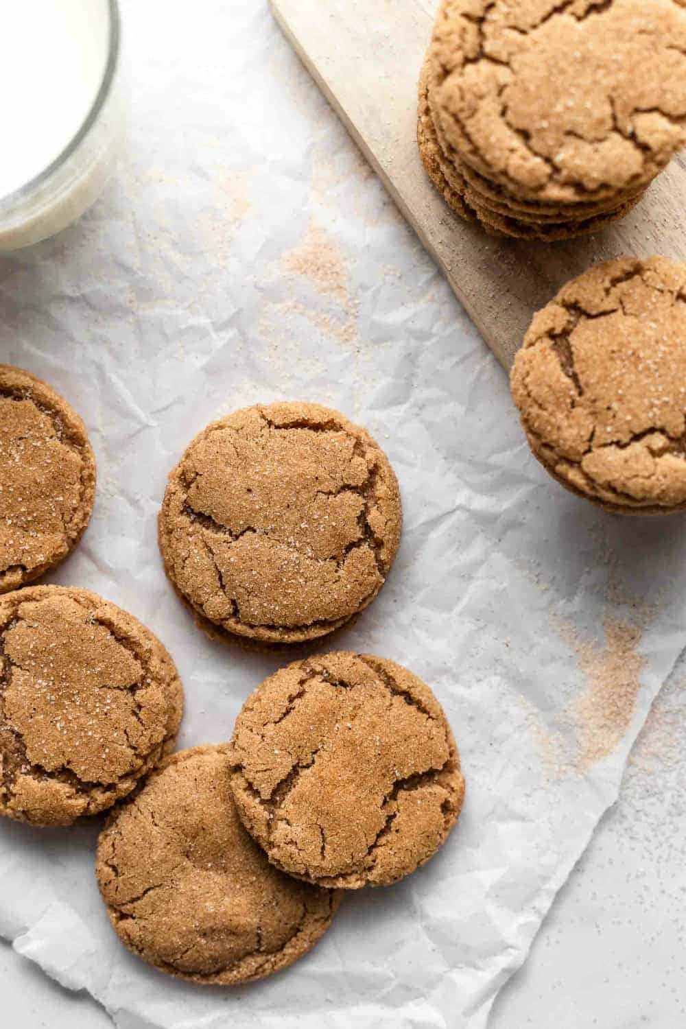 Chai sugar cookies arranged on parchment paper next to a glass of milk