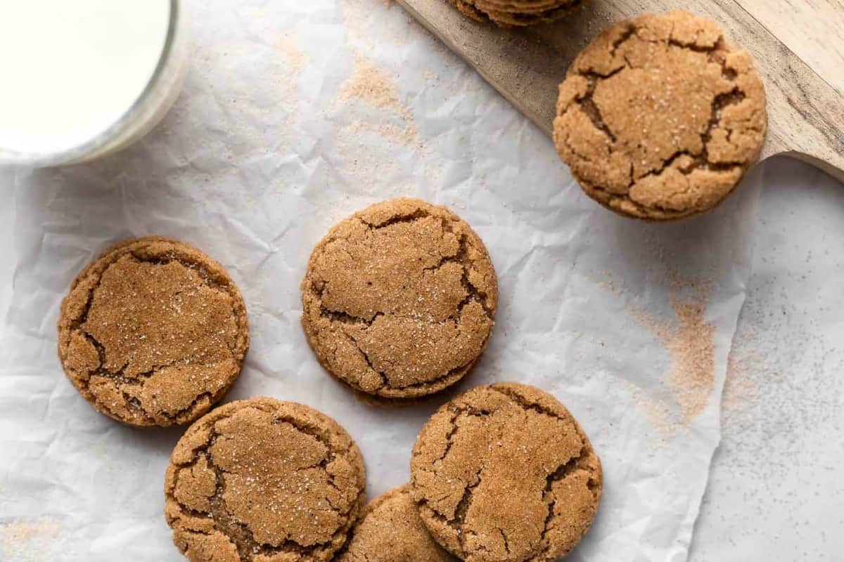 Chai sugar cookies scattered on parchment next to a glass of milk