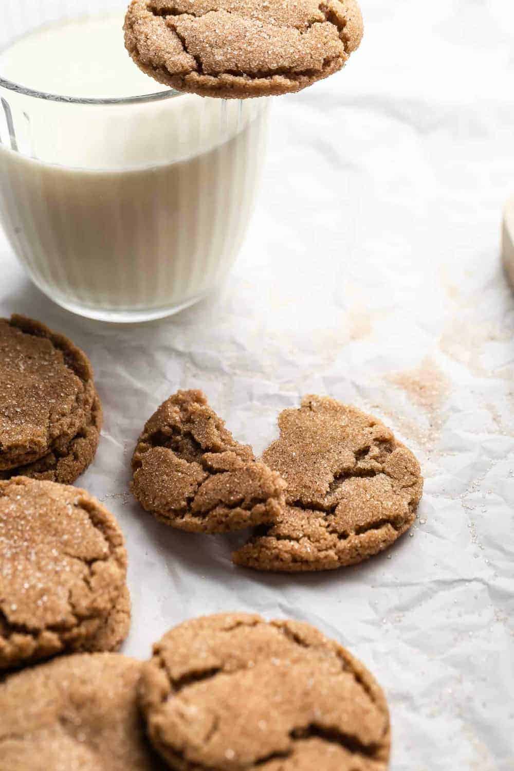 Chai sugar cookie broken in half next to a glass of milk