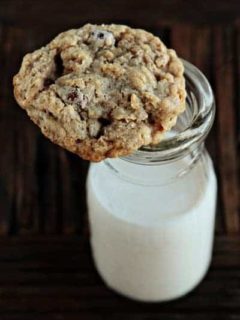 An oatmeal raisinet cookie on top of a glass of milk