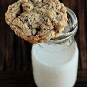 An oatmeal raisinet cookie on top of a glass of milk